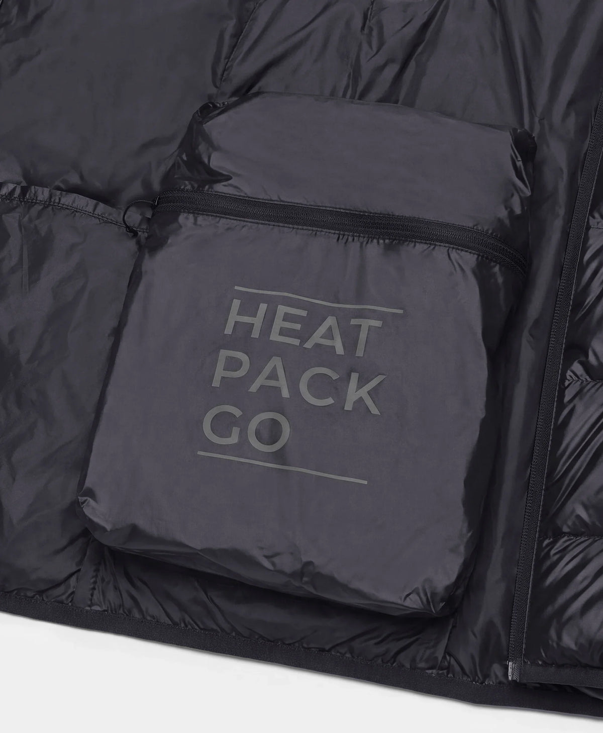 Close-up of the built-in zippered pocket labeled "HEAT PACK GO" on the inside of a black down vest
