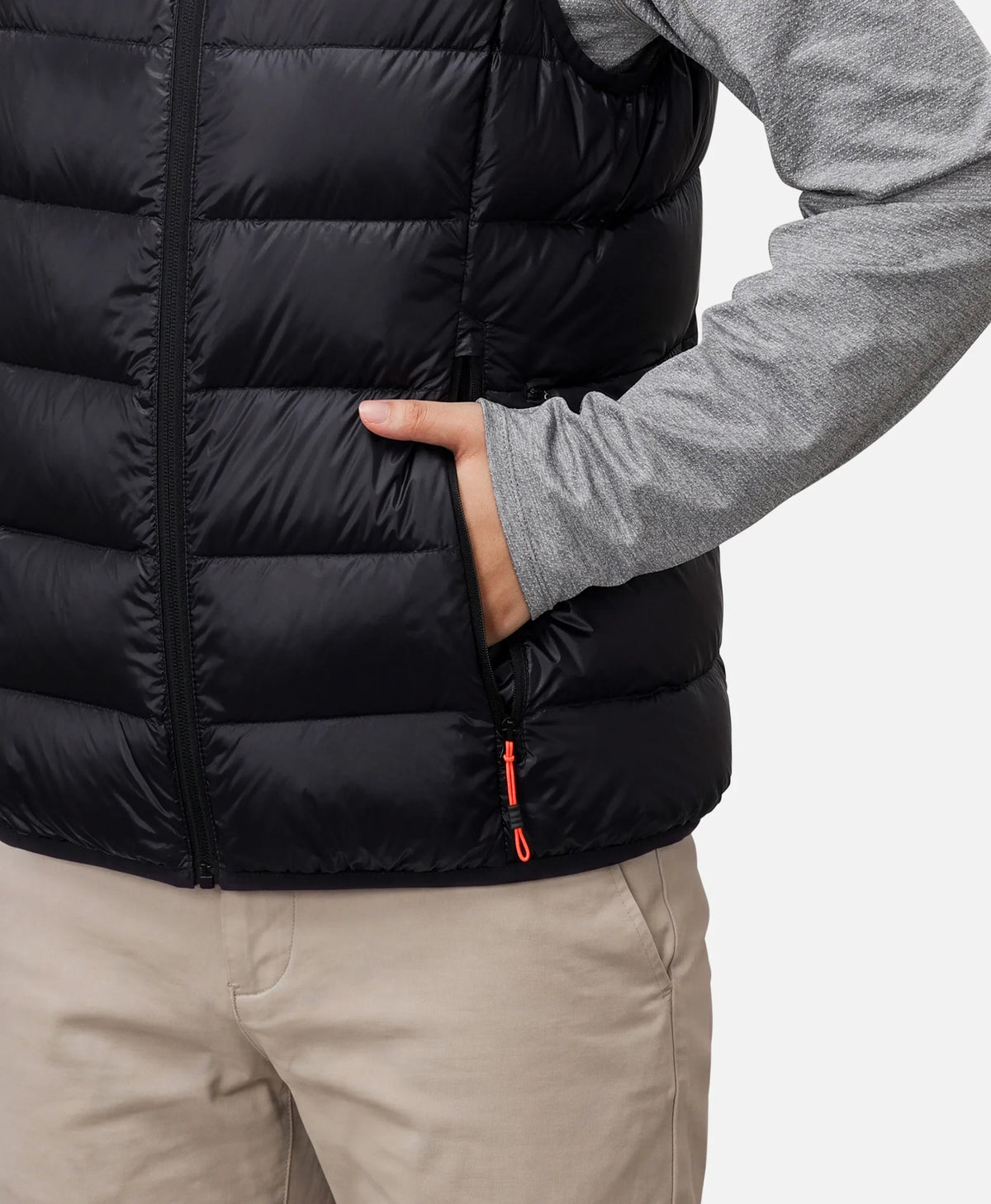 Close-up of a person putting a hand into the zippered pocket of a black vest