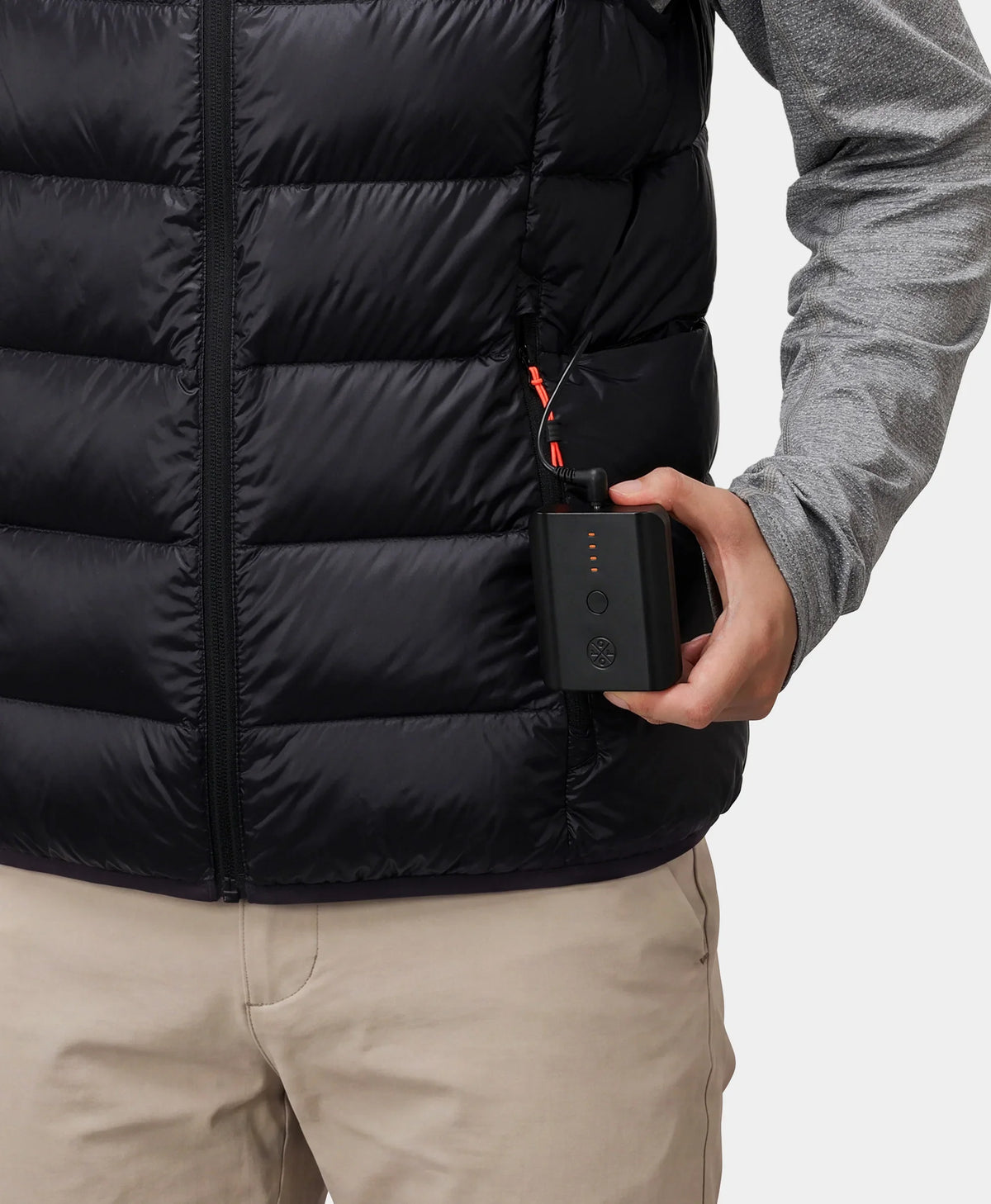 Hand putting a power bank into the zippered pocket of a black vest