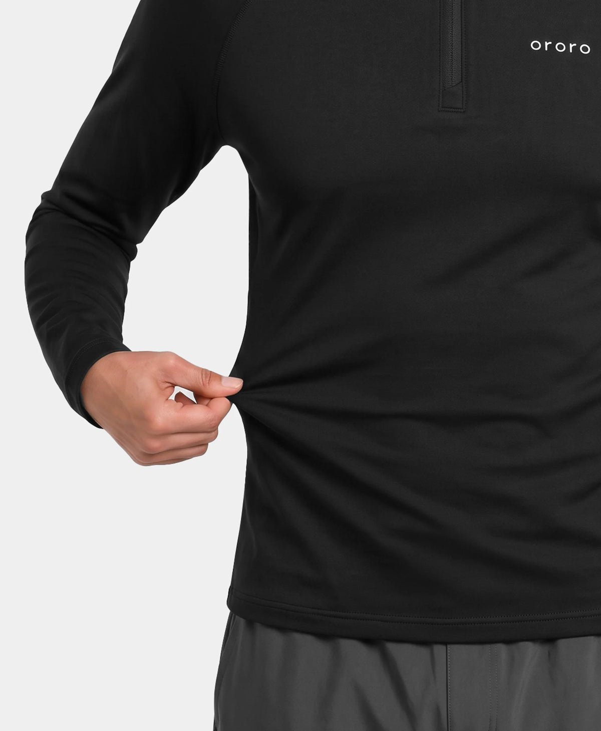 Close-up of a man pulling the hem of an ororo black heated base layer top.
