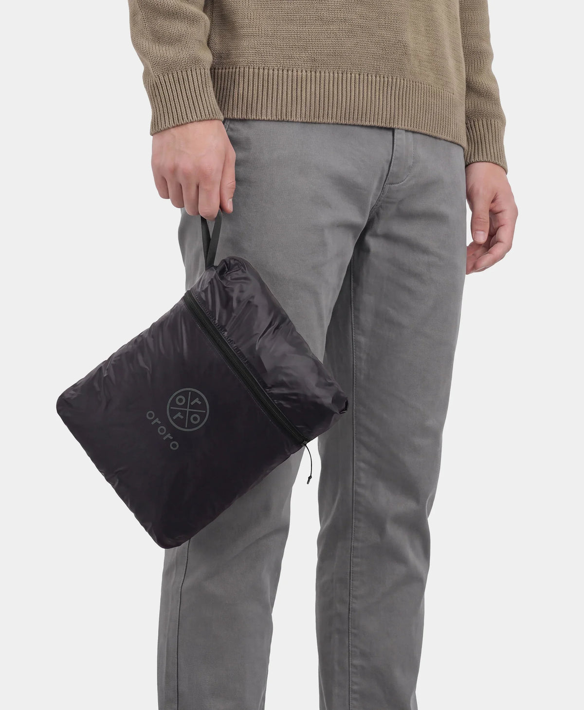 Man holding a black vest packed into its built-in zippered pouch