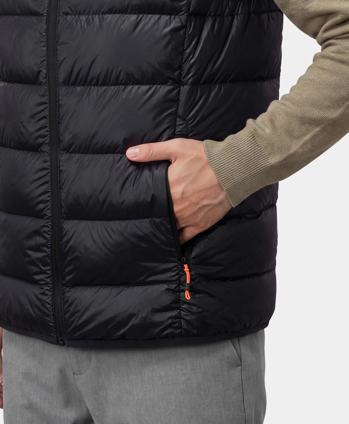 Hand putting a hand into the zippered pocket of a black vest