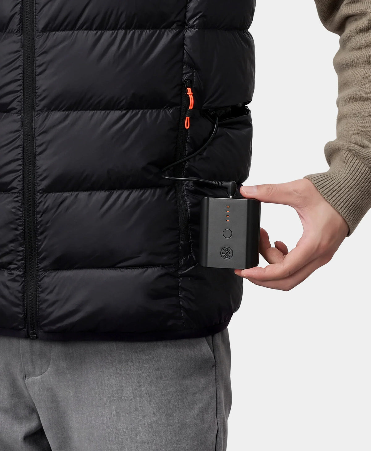 Hand putting a black power bank into the pocket of a down vest
