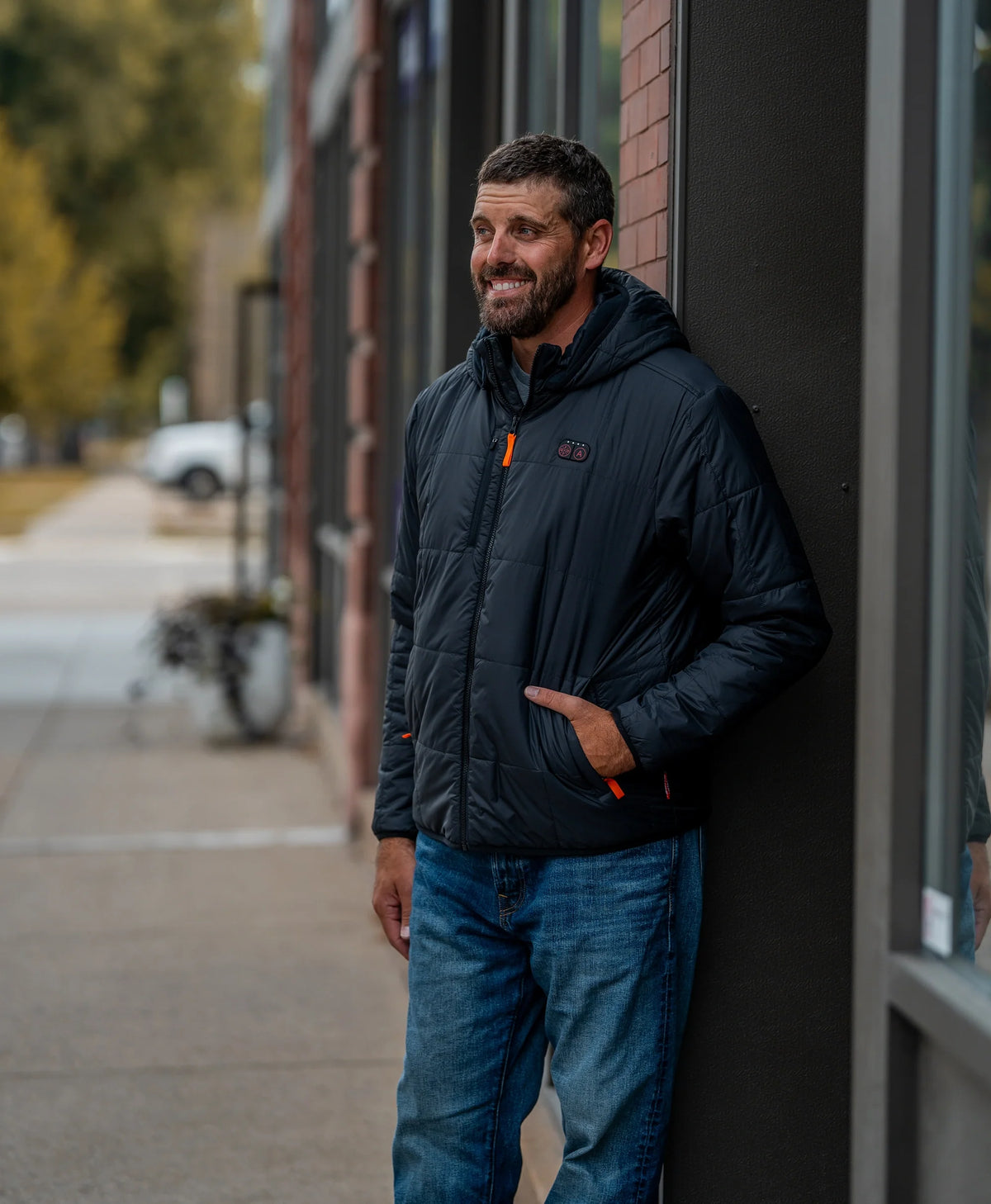 Men's Overland 7-Zone Heated Box Quilted Jacket with Heated Hood in black, worn on a city sidewalk