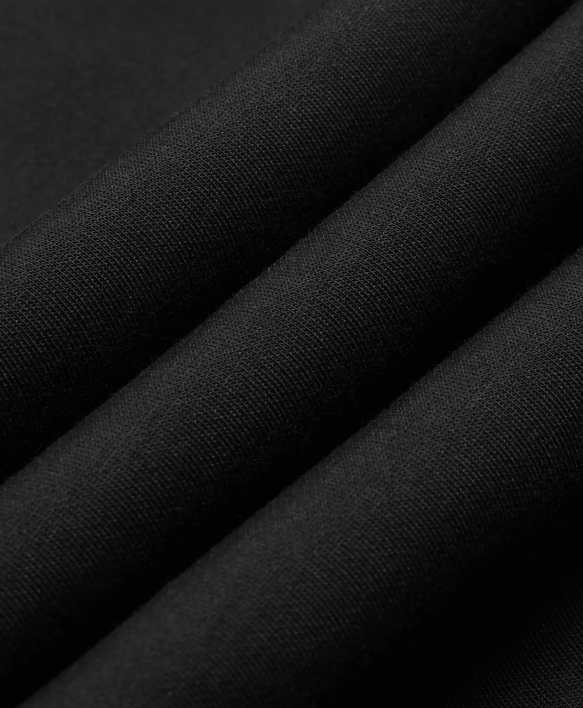 A black Toasty Unisex 5-Zone Heated Pullover Hoodie, displayed in a macro close-up of draped black fabric with soft diagonal folds showing a fine woven texture.