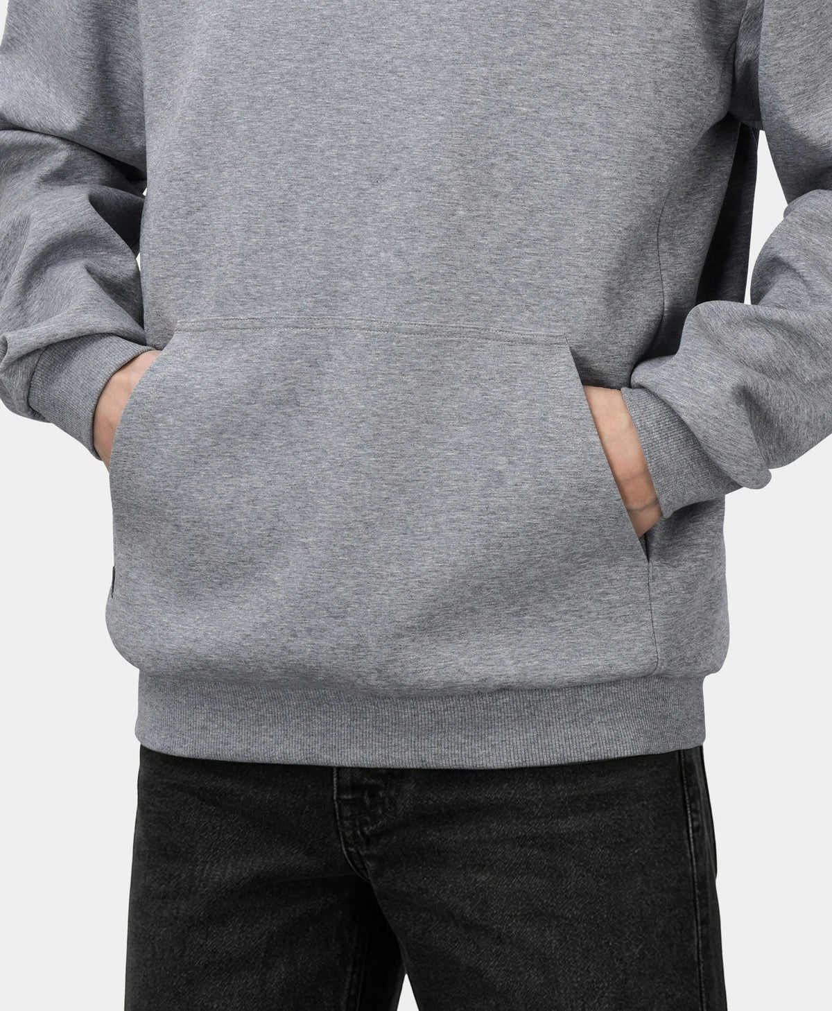 A flecking gray Toasty Unisex 5-Zone Heated Pullover Hoodie, shown in a close-up detail of the front kangaroo pocket with a model placing their hands inside.