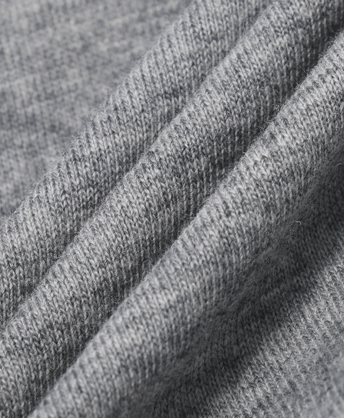 Close-up of a heather gray knit fabric with soft diagonal folds showing the texture and weave.